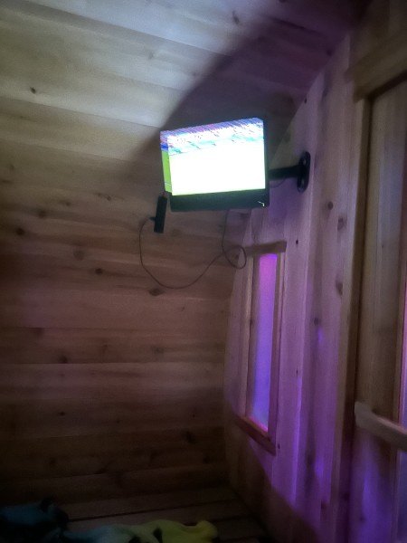 Inside the cedar sauna looking at the wall-mounted TV