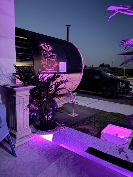 The barrel sauna set up at a home at night with purple lighting and a glowing cold plunge